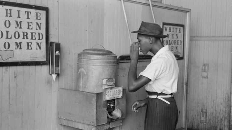 A man drinks at a "Colored" water cooler in the...