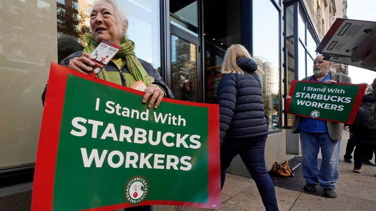 Arlene Geiger, left, holds a sign supporting Starbucks workers outside...