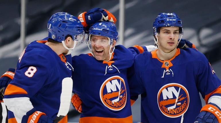 Islanders' Andy Greene (4) celebrates with teammates Noah Dobson (8)...