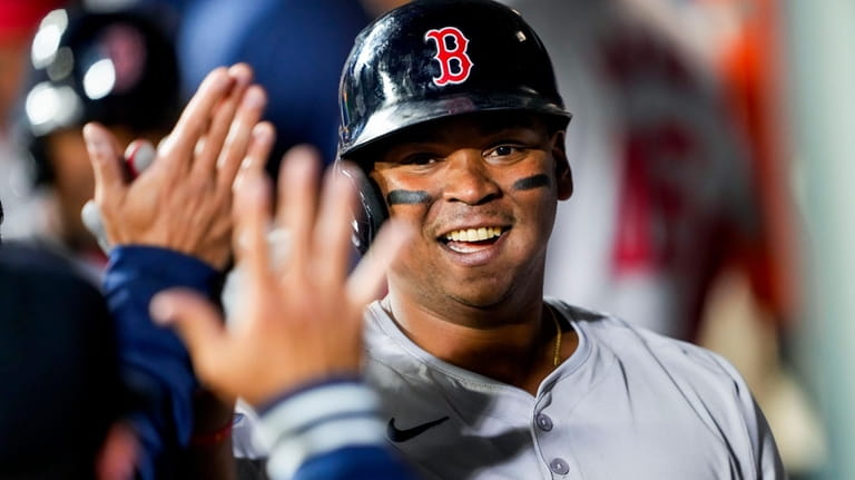 Boston Red Sox's Rafael Devers is greeted in the dugout...