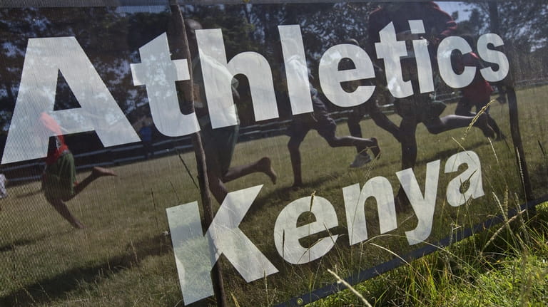 Junior athletes run past a sign for Athletics Kenya at...