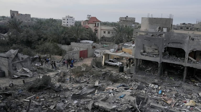 Palestinians look at buildings destroyed in the Israeli bombardment of...