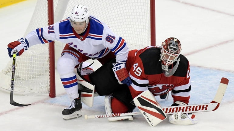 Rangers defenseman Tarmo Reunanen becomes entangled with Devils goaltender Jonathan...