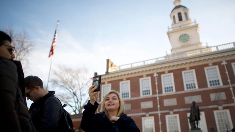 A tourist takes a selfie in front of Independence Hall in...