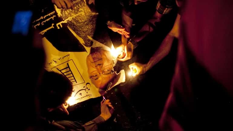 Egyptian demonstrators set fire to campaign sign of Ahmed Shafik,...