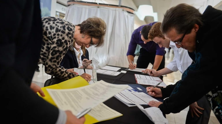 Job seekers fill out applications at the Coach table while...