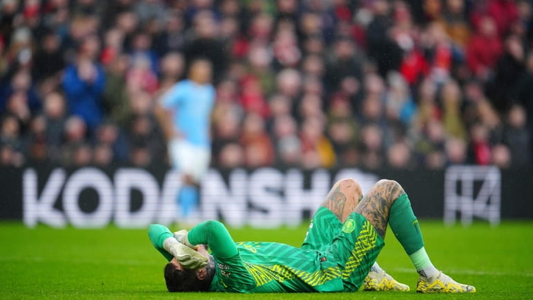 Manchester City's goalkeeper Ederson lies on the ground after an...