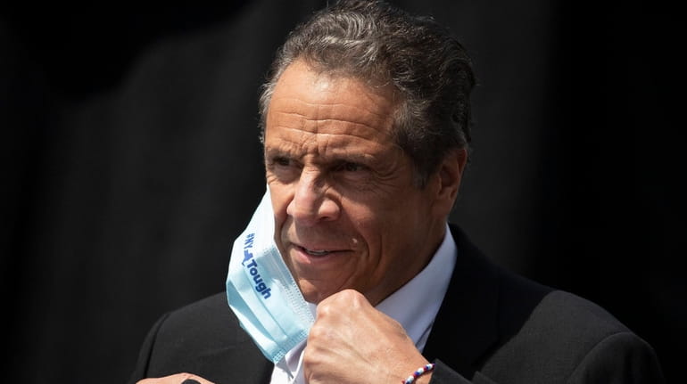 New York Gov. Andrew Cuomo removes a mask as he...