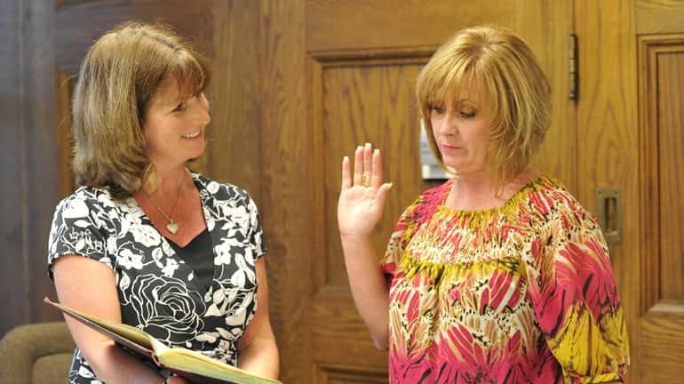 Kings Park School District clerk Patti Capobianco, left, administers the...