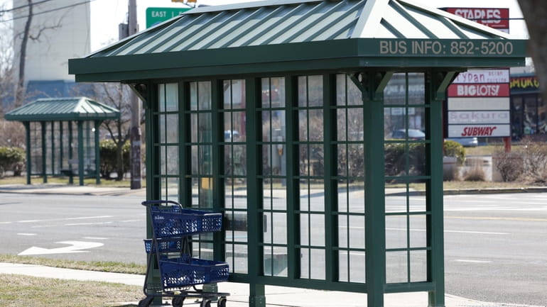 A shopping cart sat abandoned by a bus stop Monday outside stores...