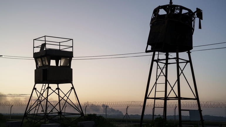 Old observation towers stand near a fence as smoke rises...