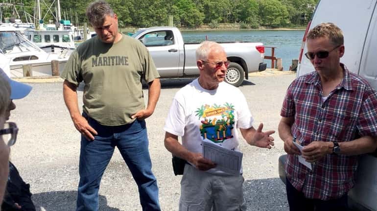 Riverhead fisherman Phil Karlin, center in white, discusses the hardship...