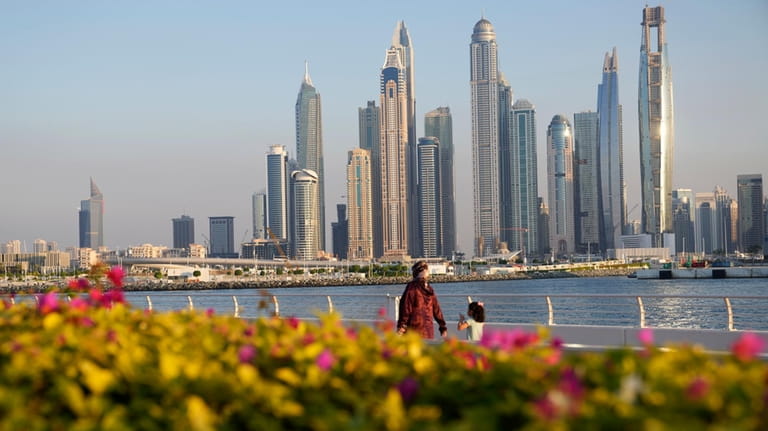 People walk with the skyline in the background as Dubai,...
