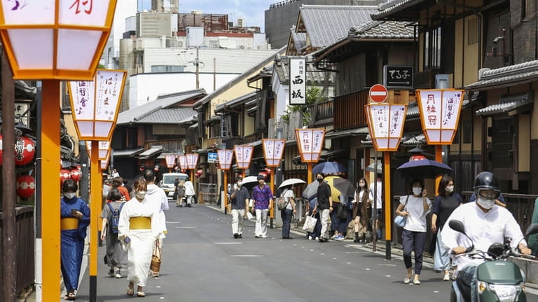 People walk along a street in Gion area, Kyoto, western...