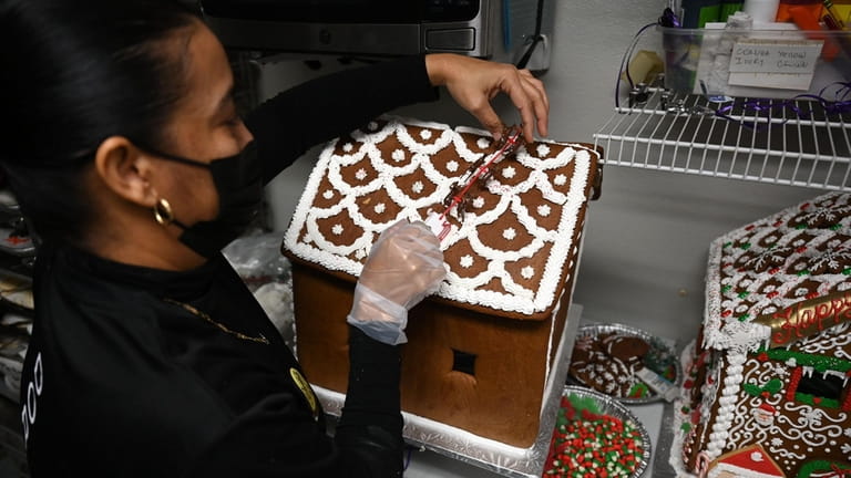 Yamirys Raposo decorates a gingerbread house at Dortoni Bakery in...
