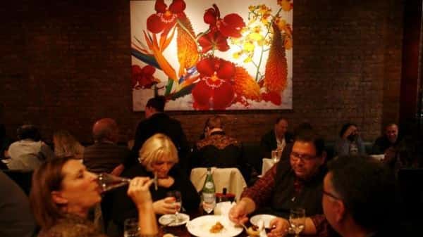 Diners sit under a tropical painting hung on an exposed-brick...
