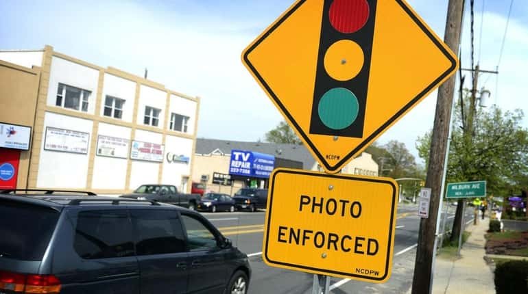 A red-light traffic camera sign is pictured at the intersection...