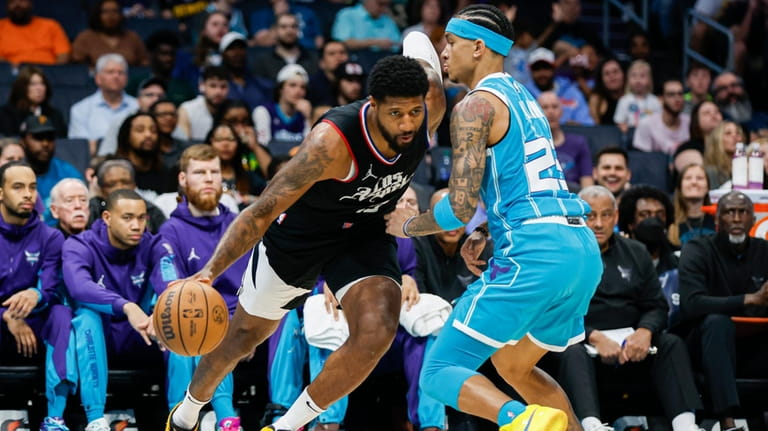 Los Angeles Clippers forward Paul George, left, drives into Charlotte...
