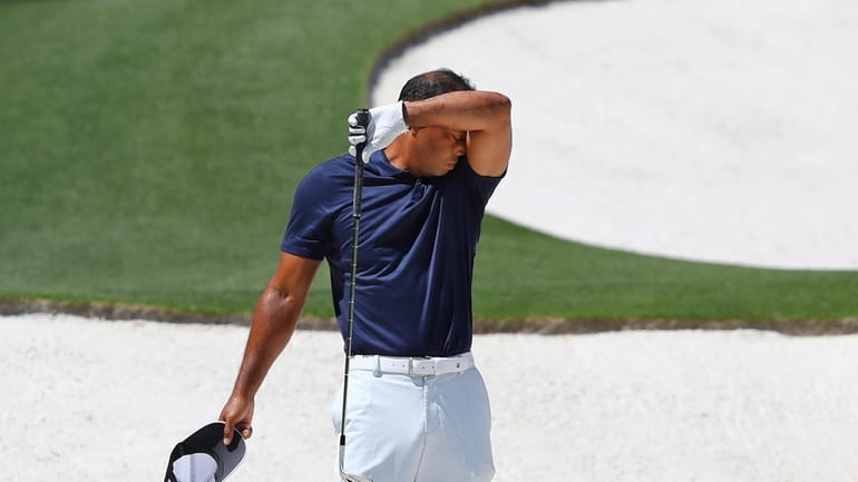 Tiger Woods pauses while getting in some work chipping at...
