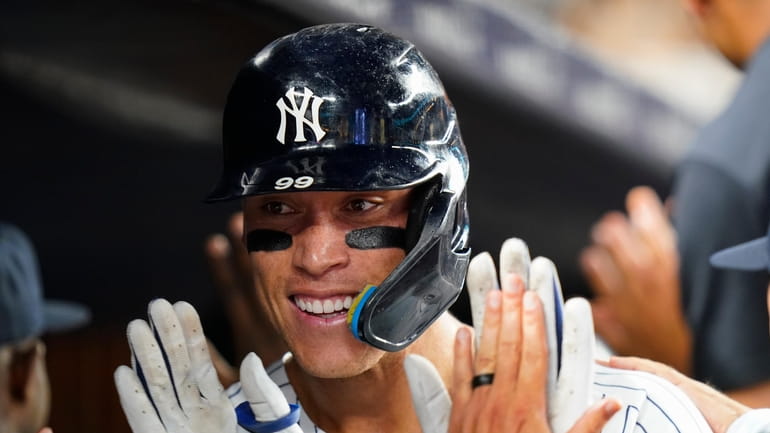 Aaron Judge celebrates with Yankees teammates after hitting a grand...