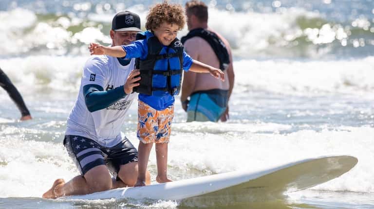 Jayce Figueroa, 5, of Brooklyn catches a wave with help...