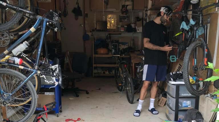Sean Logan, of Babylon, fixes bicycles in his garage.