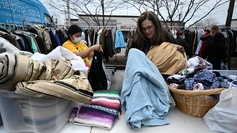 The Rev. Kim Gaines-Gambino, right, helps sort blankets and clothing...