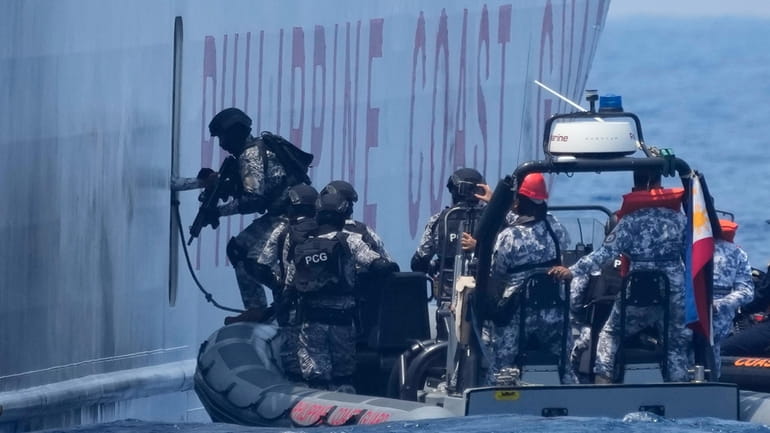Armed Philippine Coast Guard personnel board the PCG Melchora Aquino...