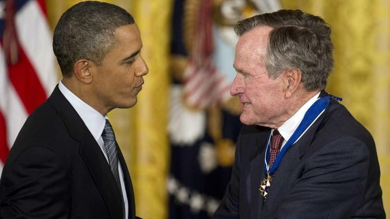President Barack Obama congratulates former President George H.W. Bush after...