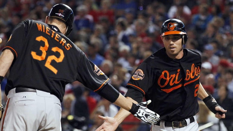 Baltimore Orioles shortstop J.J. Hardy celebrates with Matt Wieters after...