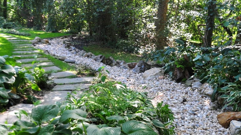 The finished riverbed has a gravel-covered rubber liner surrounded by decorative...