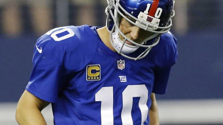 Eli Manning (10) leaves the field after throwing an interception...