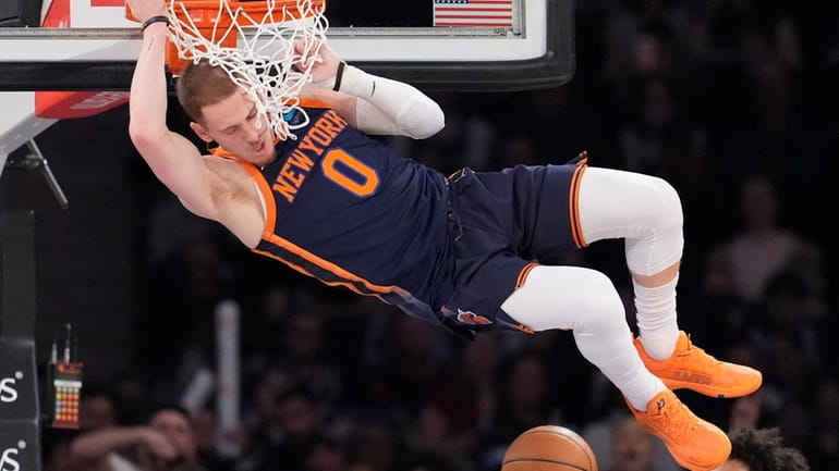 New York Knicks guard Donte DiVincenzo hangs from the rim...