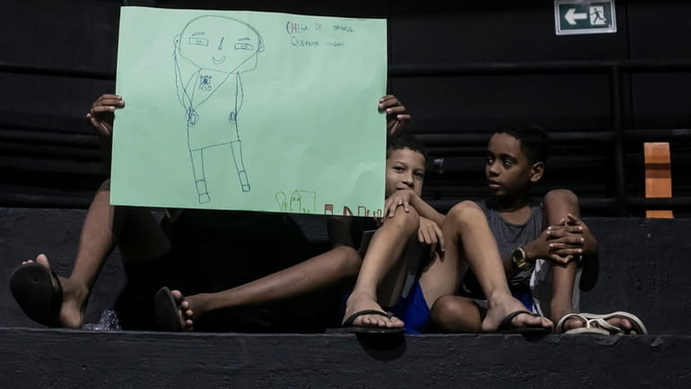Children hold drawings that represent their experiences of living in...