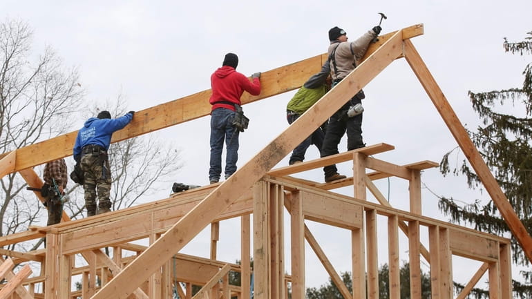 Carpenters frame a roof on a new home under construction...
