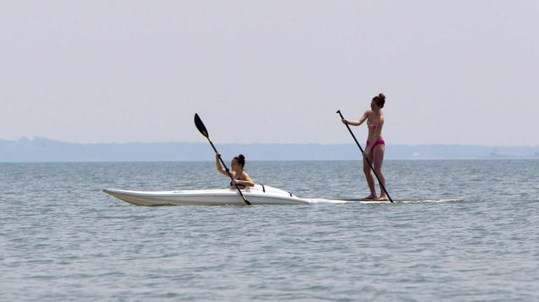 A kayaker and stand up paddler glide across the Peconic...