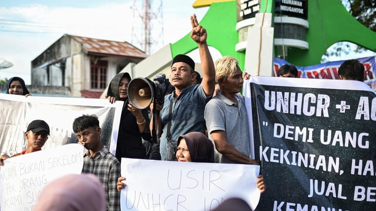 Protesters hold posters during a rally in Sabang, Aceh province,...