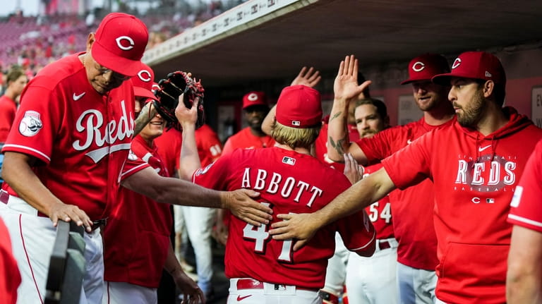 Cincinnati Reds' Andrew Abbott, center, high-fives teammates in the dugout...