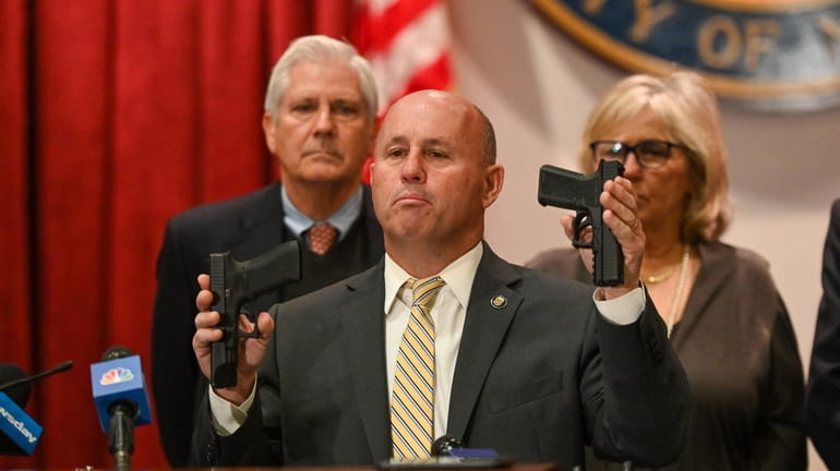 Nassau County Police Commissioner Patrick Ryder holds up two ghost handguns...