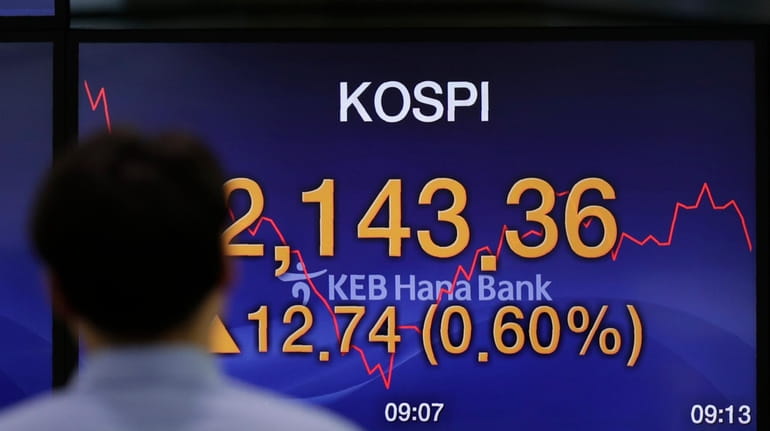A currency trader walks by the screen showing the Korea...