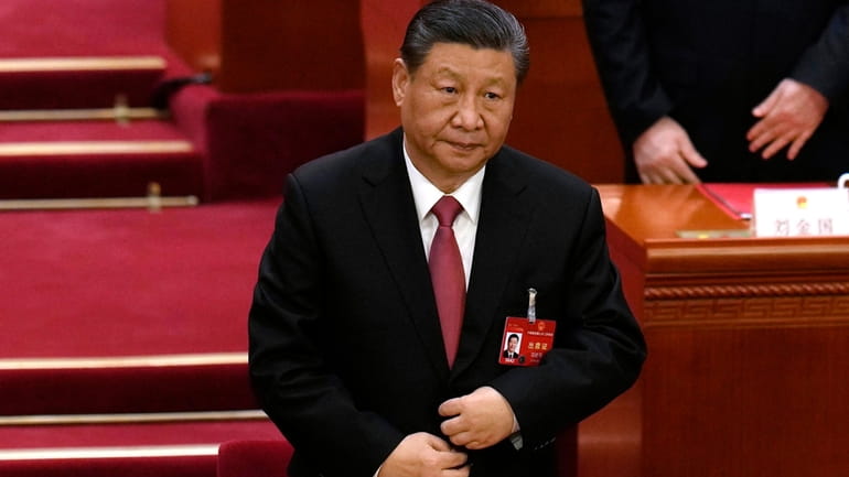 Chinese President Xi Jinping adjusts his jacket as he stands...