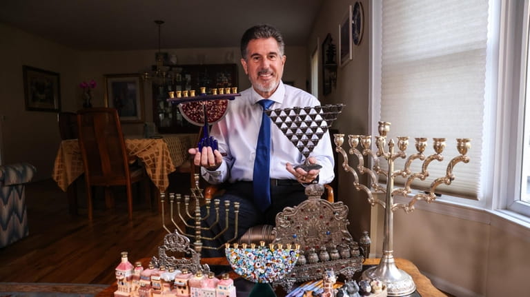 Rabbi Howard Buechler with his menorah collection at his Dix...