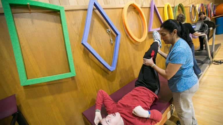 Physical therapist Gloria Ghani works with Dylan Maag, 14, of...