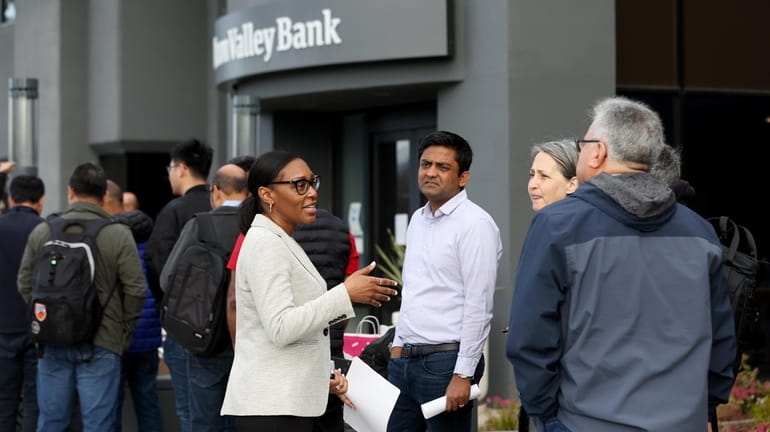 A Silicon Valley Bank worker talks with people lining up...