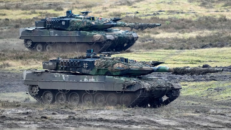 Two Leopard 2 tanks are seen in action during a...