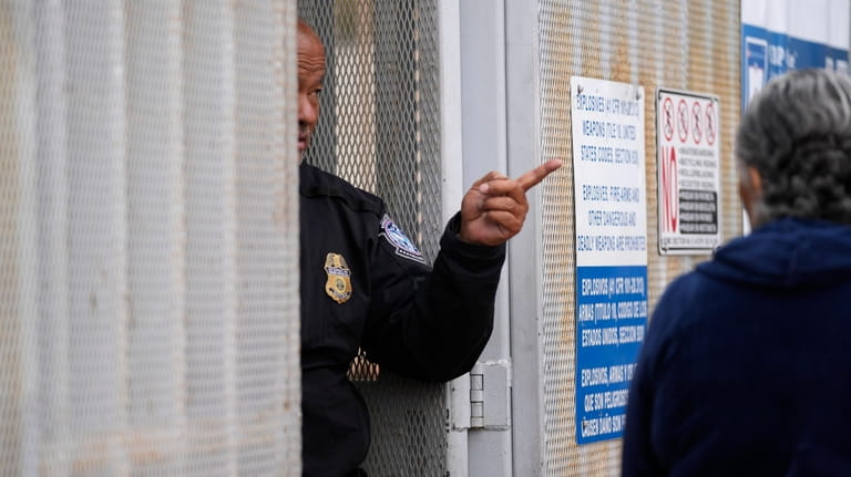 A United States Customs and Border Protection officer points towards...