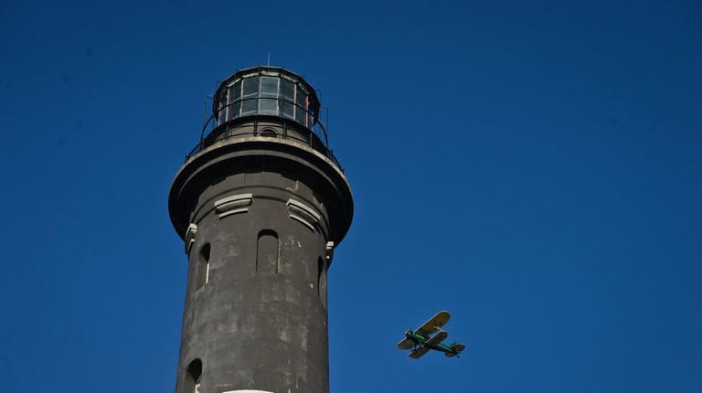 An airplane with presents flies past the lighthouse during a...