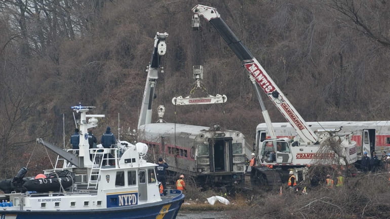 Workers right and move a derailed Metro-North train car in...