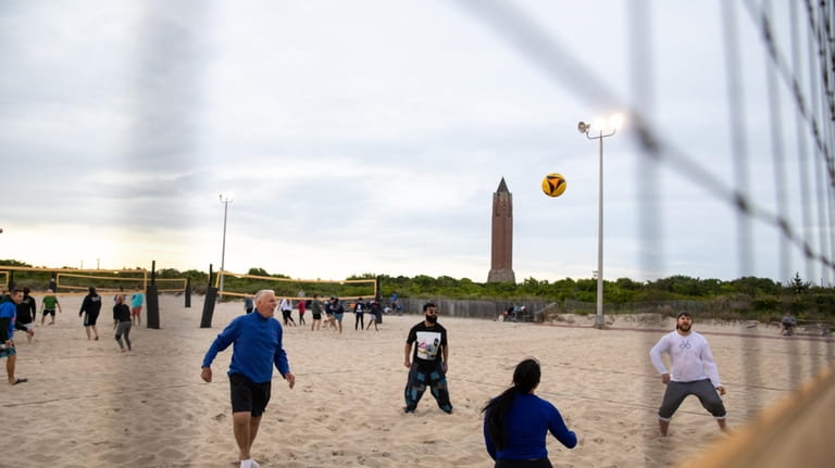 Beachgoers play volleyball near sundown at Jones Beach in Wantagh,...