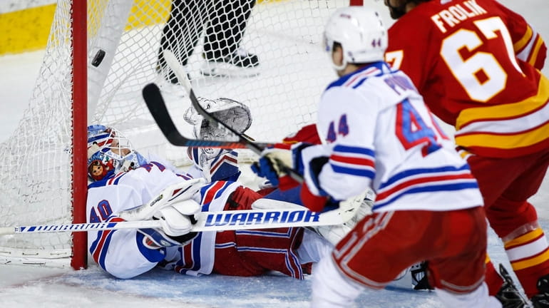 Rangers goalie Alexandar Georgiev, left, is caught on his back...
